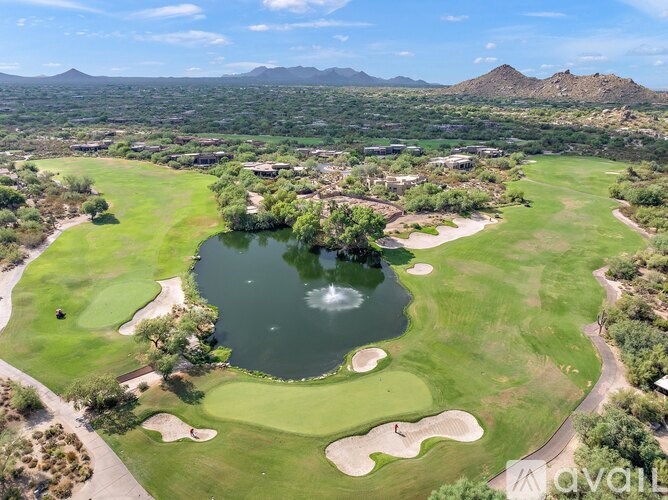 A golf course with a green and a pond in the middle of it.
