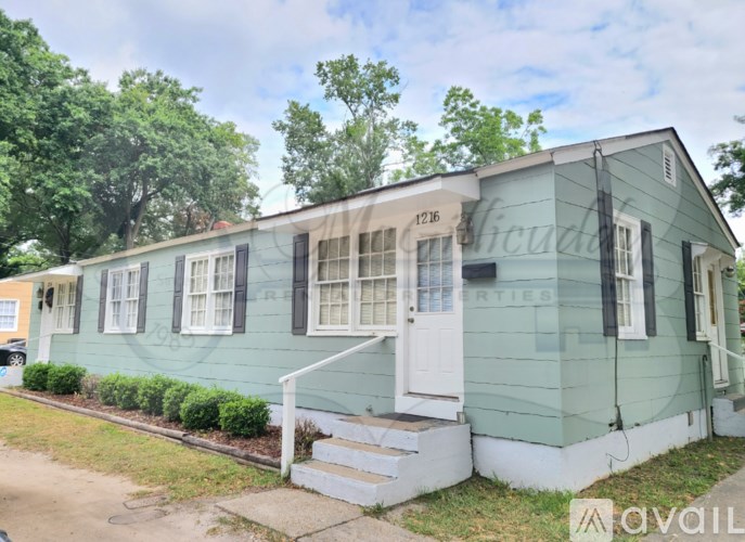 A green house with a white door and windows is for rent.