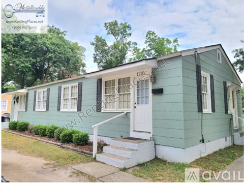 A green house with a white door and windows is for rent.