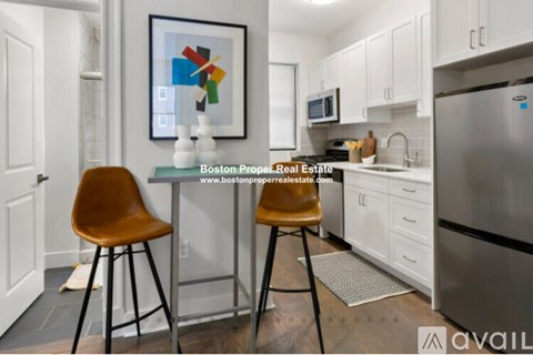 A kitchen with a fridge, a table and chairs, and a painting on the wall.