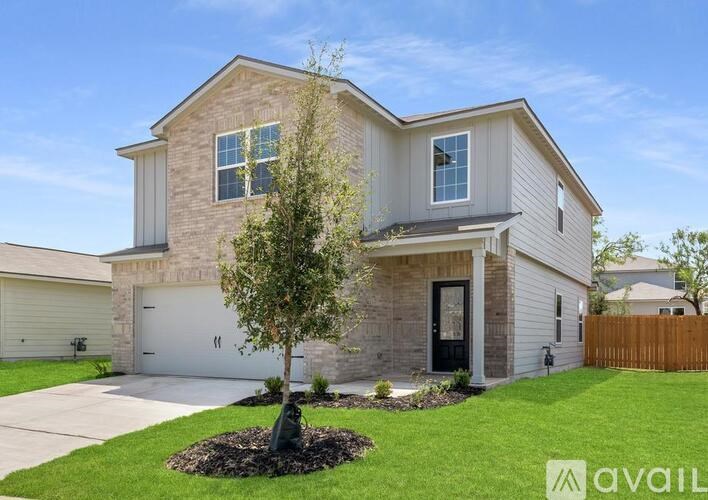 A house with a garage and a tree in front.