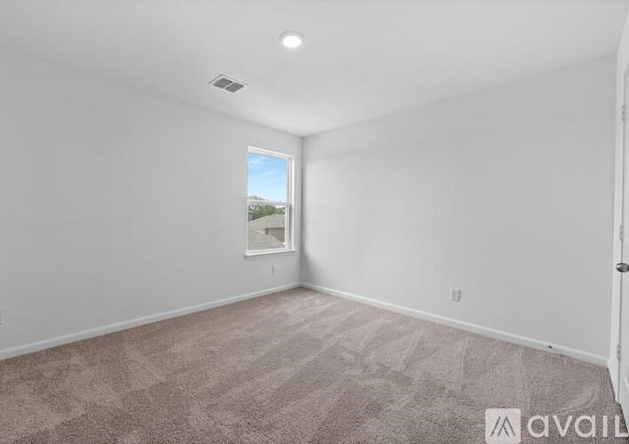 A room with a carpeted floor and a window showing a view of the outside.