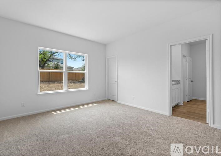 A spacious room with a large window and a door leading to another room.