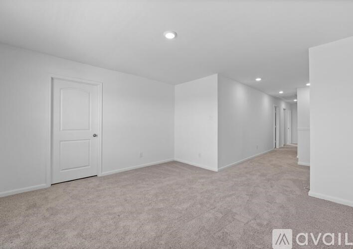 A spacious room with a carpeted floor and white walls.