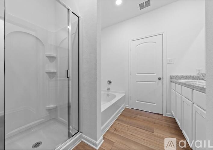 A bathroom with a walk-in shower and a white door.