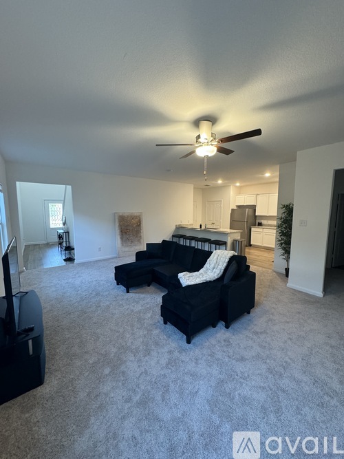 A living room with a black couch and a ceiling fan.