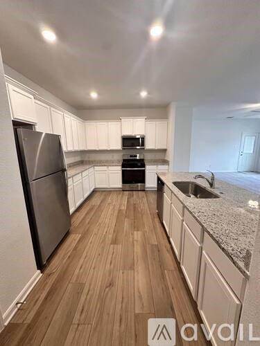 A kitchen with a refrigerator, sink, and cabinets.