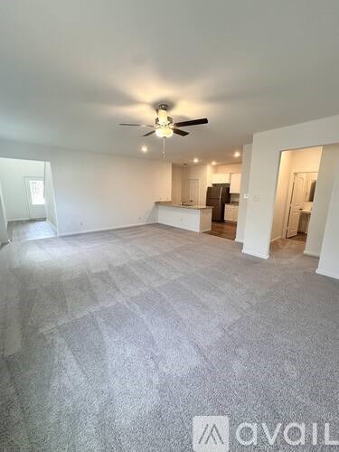 A spacious room with a ceiling fan and carpeted floor.