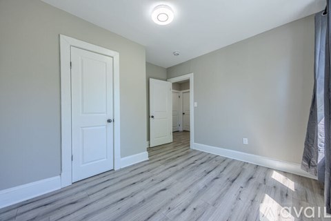 A room with a white door and a grey wall.