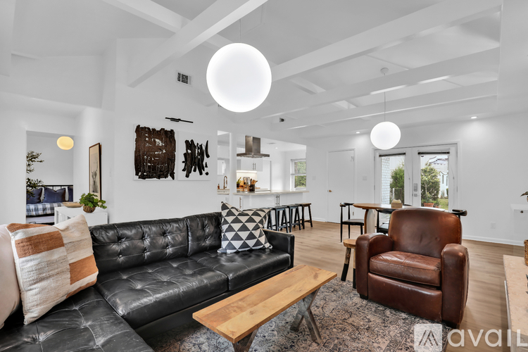 A living room with a black leather couch and a wooden coffee table.