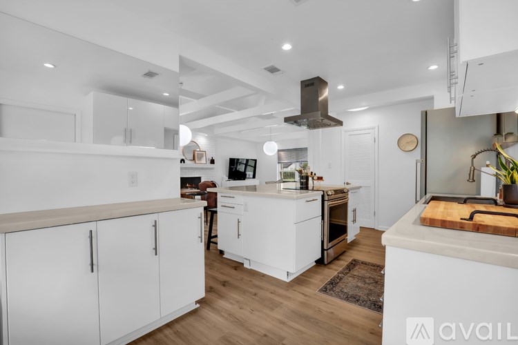 A modern kitchen with white cabinets and a wooden floor.