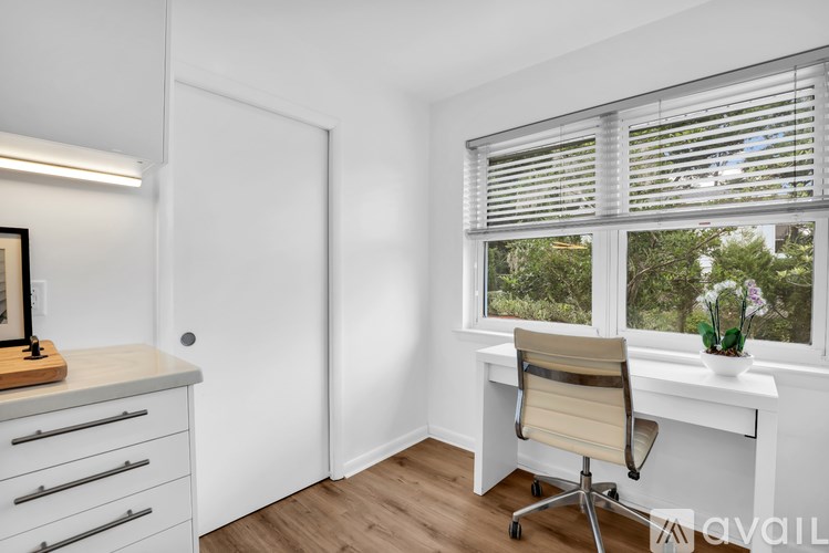A room with a desk, chair, and a window with blinds.