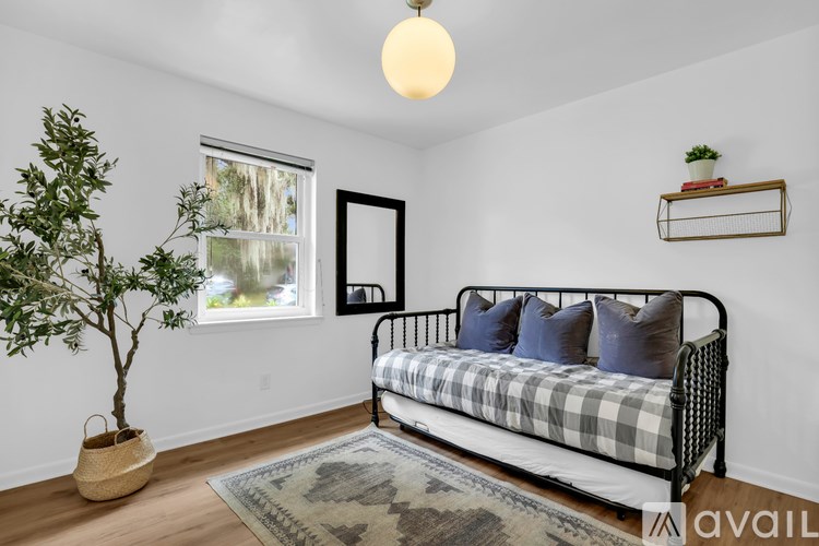 A bedroom with a bed, a tree, and a window.