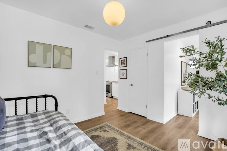 A bedroom with a bed, a plant, and pictures on the wall.