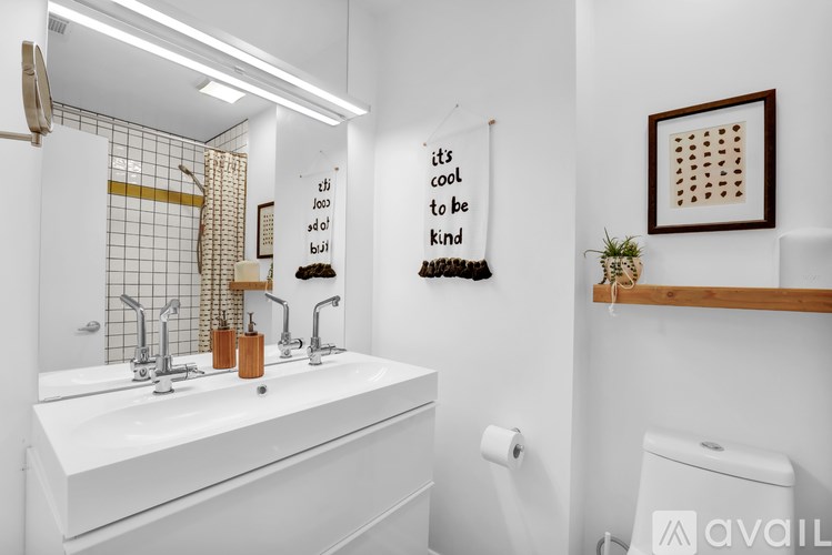 A bathroom with a white sink and a poster that says "it's cool to be kind".