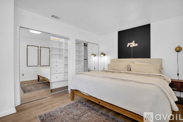 A bedroom with a large bed and a mirrored closet door.