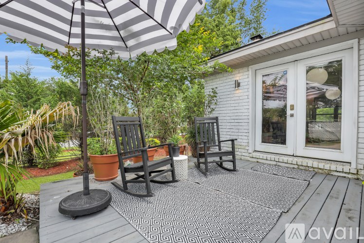 A patio with a striped umbrella and two chairs.