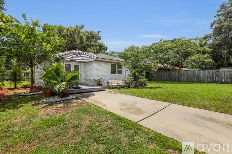 A house with a white exterior and a patio with a table and chairs.
