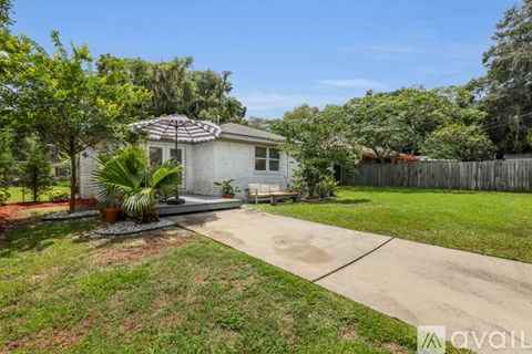 A house with a white exterior and a patio with a table and chairs.