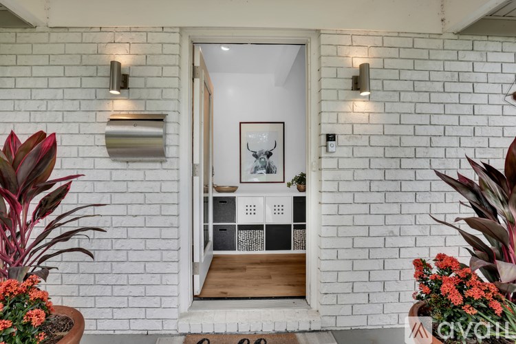 A white brick wall with a framed picture of a cow and a white door.