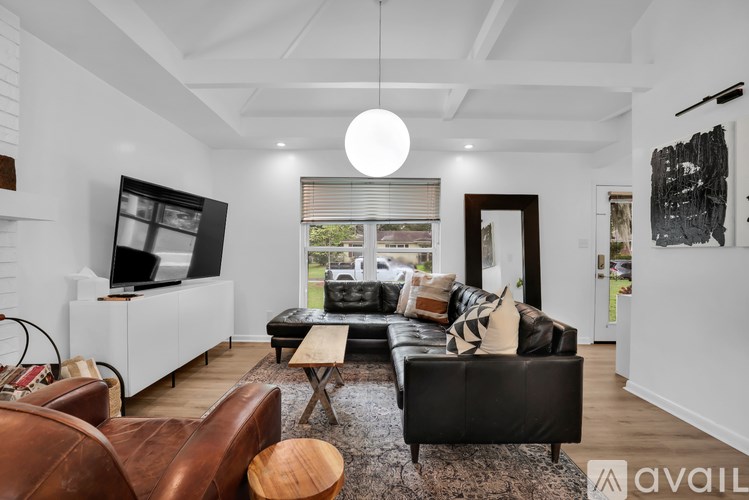 A modern living room with a black leather couch and a brown leather chair.