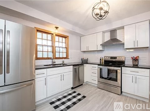 A kitchen with white cabinets and a black and white checkered floor mat.