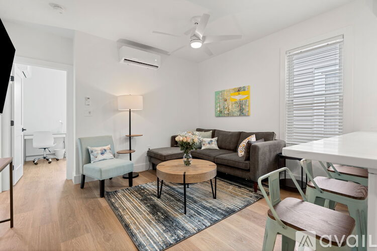A living room with a grey couch, a white table, and a painting on the wall.