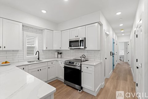 A modern kitchen with white cabinets and appliances.