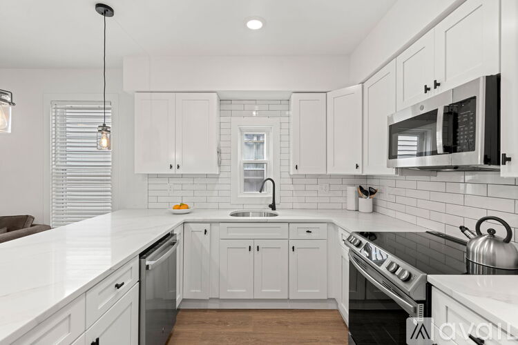 A modern kitchen with white cabinets and a wooden floor.