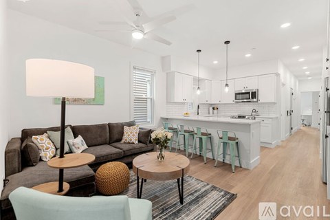 A modern living room with a grey couch, a round table with a vase of flowers, and a rug on the floor.