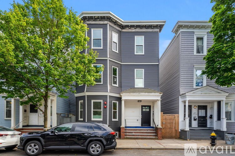 A black SUV is parked in front of a two-story house.