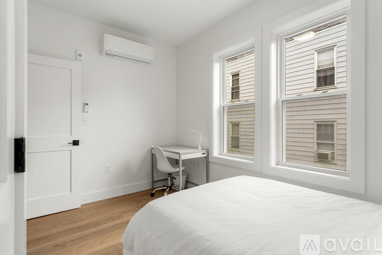 A bedroom with a bed, desk, and window.