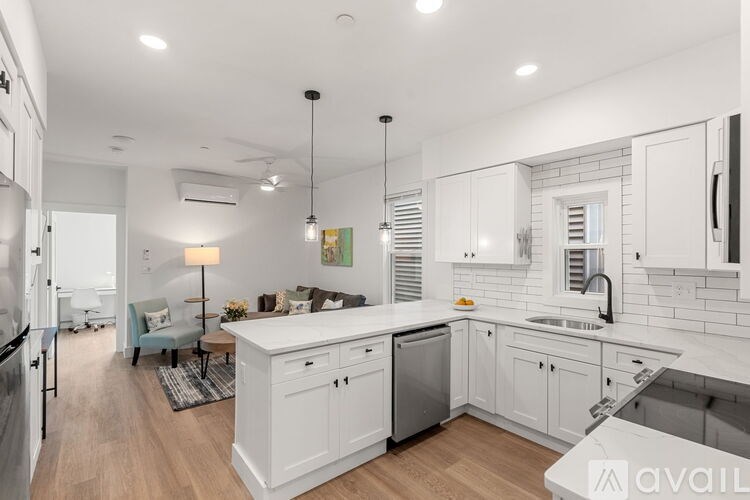 A modern kitchen with white cabinets and a wooden floor.