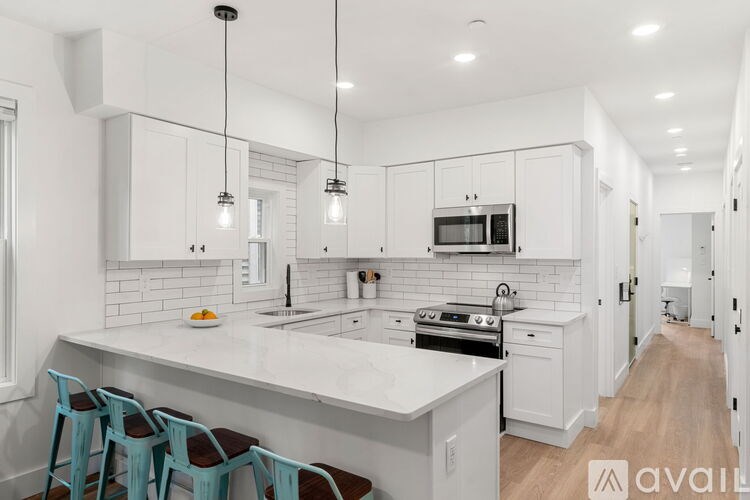 A kitchen with white cabinets and a large island with blue chairs.