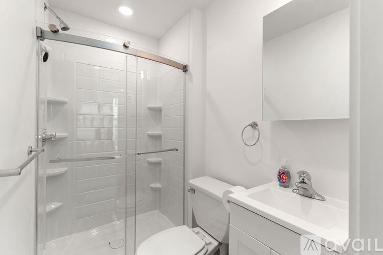 A white bathroom with a toilet, sink, and walk-in shower.