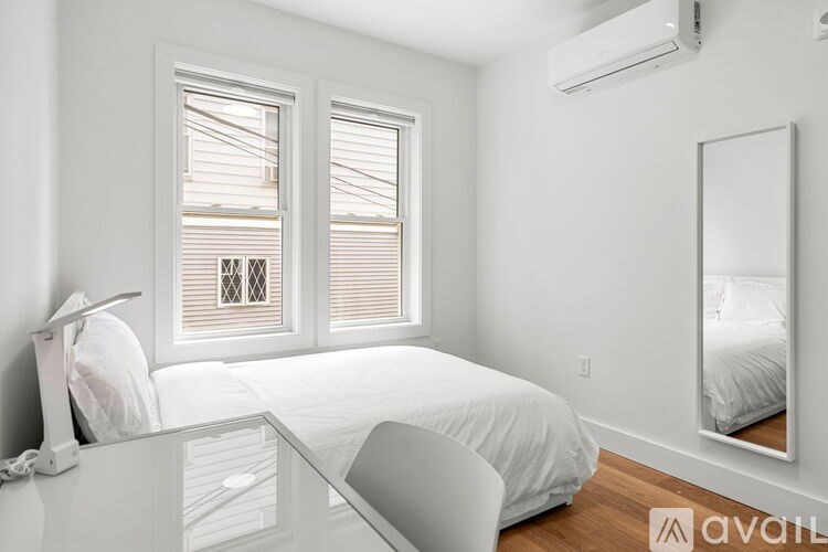 A white bedroom with a bed, desk, and chair.