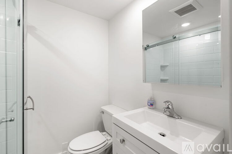 A white bedroom with a bed, a fridge, and a TV.