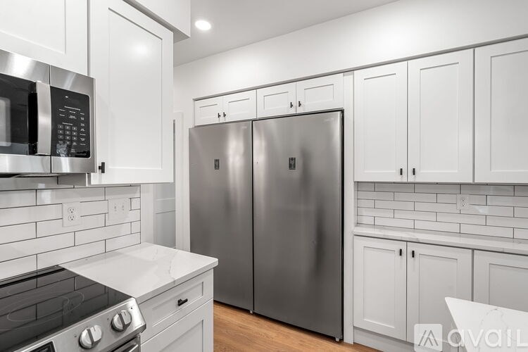 A modern kitchen with a stainless steel refrigerator and white cabinets.