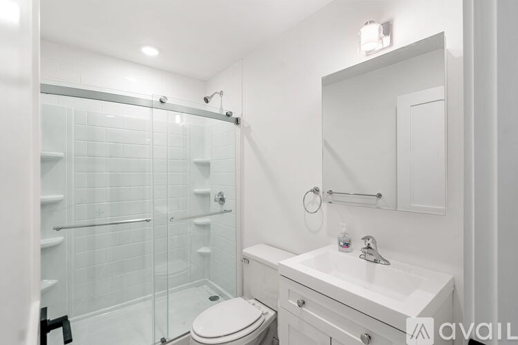 A white bathroom with a toilet, sink, and shower.
