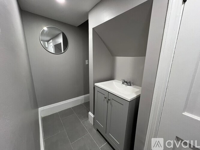 A bathroom with a round mirror and a sink with a cabinet.