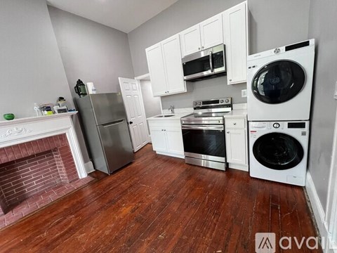 A kitchen with white cabinets and a wood floor.