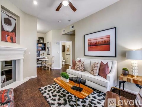 A living room with a white couch, a coffee table, and a painting on the wall.