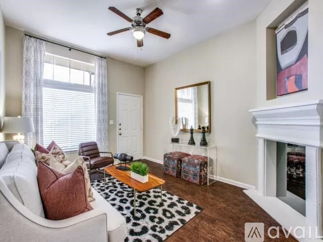 A living room with a white couch, a fireplace, and a rug.
