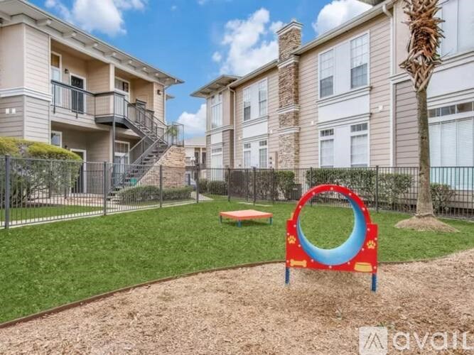 A playground with a red and blue slide in front of apartment buildings.