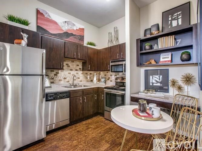 A modern kitchen with a refrigerator, microwave, oven, and sink.