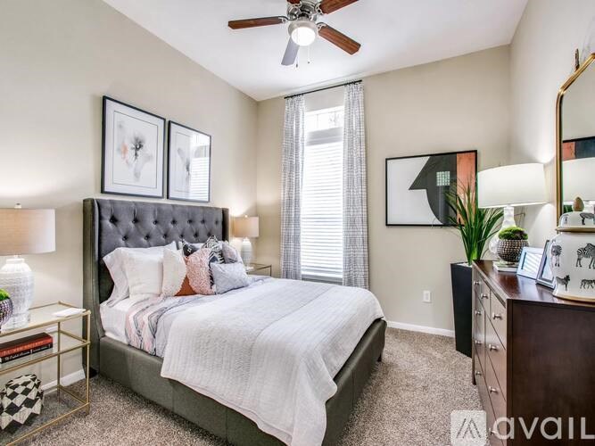 A bedroom with a large bed, a ceiling fan, and a nightstand with a lamp.
