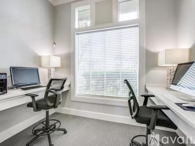A room with two chairs and two computers on desks.