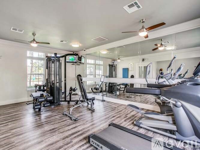 A gym with a variety of equipment including treadmills, weights, and exercise machines.