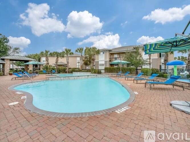 A large outdoor swimming pool surrounded by a brick patio and lounge chairs.