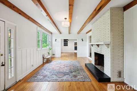 A large, open living room with a fireplace and a rug on the floor.